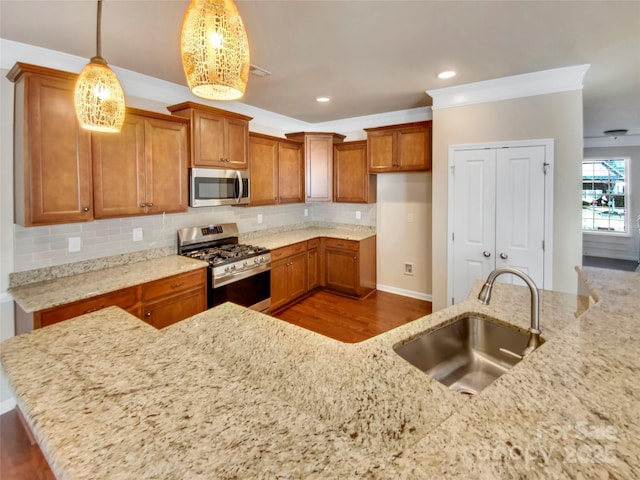 kitchen featuring sink, light stone counters, hanging light fixtures, stainless steel appliances, and decorative backsplash