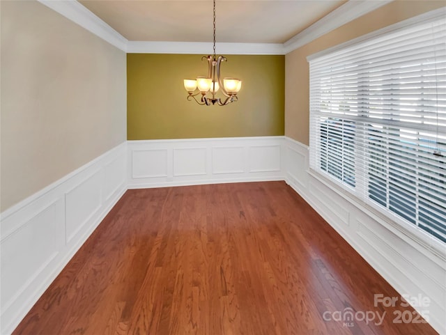 unfurnished room featuring a notable chandelier, crown molding, and hardwood / wood-style floors