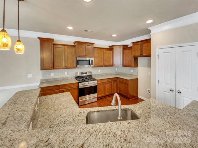 kitchen with sink, pendant lighting, stainless steel appliances, light stone countertops, and decorative backsplash