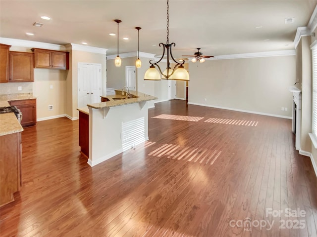 kitchen featuring hanging light fixtures, ornamental molding, light stone countertops, and dark hardwood / wood-style floors