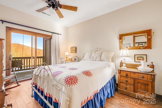 bedroom featuring a mountain view, light hardwood / wood-style flooring, ceiling fan, and access to exterior