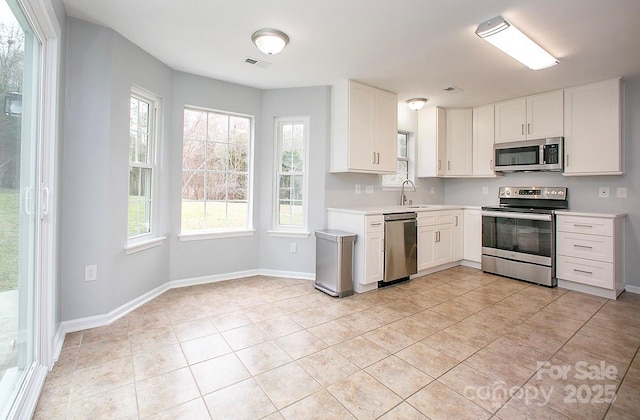 kitchen with sink, light tile patterned floors, stainless steel appliances, and white cabinets