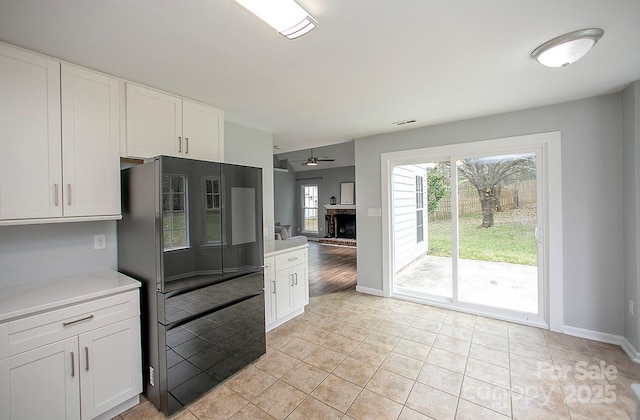 kitchen with black fridge, white cabinetry, ceiling fan, and light tile patterned floors