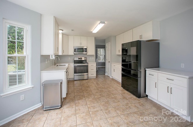 kitchen with light tile patterned flooring, appliances with stainless steel finishes, sink, and white cabinets