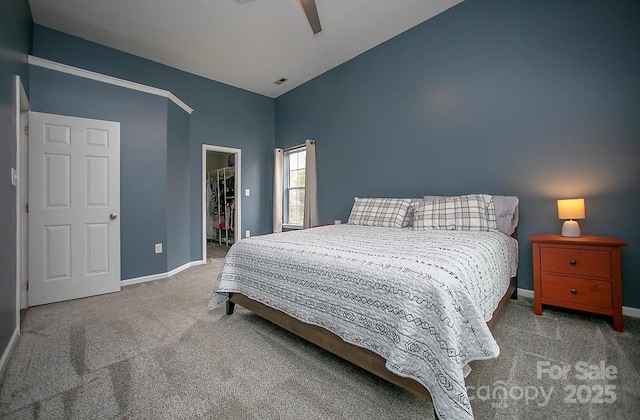 bedroom featuring vaulted ceiling, a walk in closet, light colored carpet, ceiling fan, and a closet