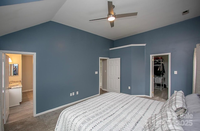 bedroom with a walk in closet, vaulted ceiling, carpet floors, a closet, and ceiling fan