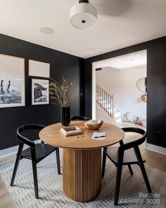 dining space with light wood-type flooring, baseboards, and stairs