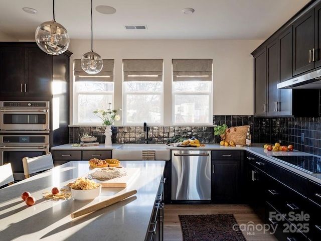 kitchen with stainless steel appliances, visible vents, under cabinet range hood, and decorative backsplash