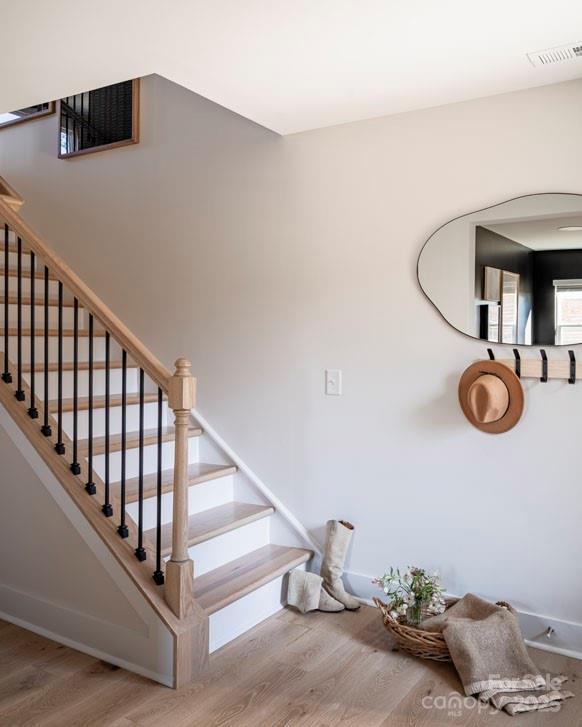 stairway with baseboards, visible vents, and wood finished floors