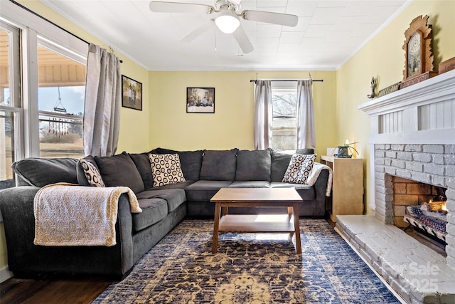 living room featuring dark wood-style floors, ceiling fan, a fireplace, and ornamental molding