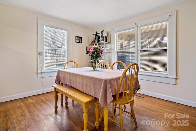 dining area featuring crown molding, baseboards, and wood finished floors