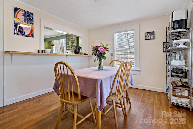 dining space featuring ornamental molding, a healthy amount of sunlight, and wood finished floors