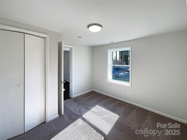 unfurnished bedroom featuring dark carpet and a closet