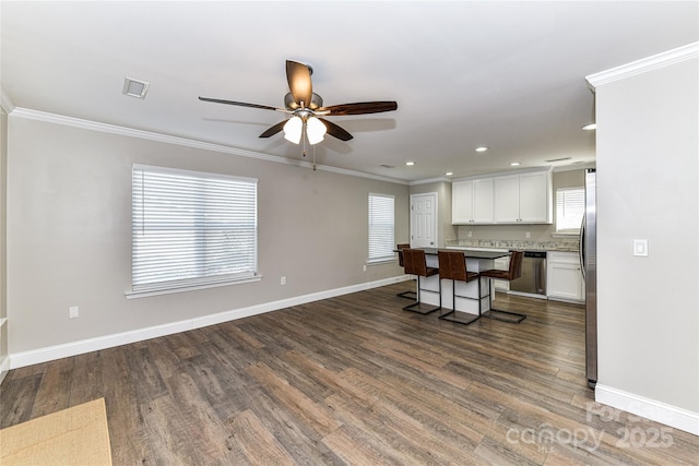 kitchen with a breakfast bar, a center island, stainless steel appliances, light countertops, and white cabinetry