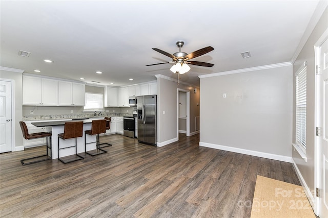 kitchen featuring a center island, a breakfast bar, stainless steel appliances, light countertops, and white cabinetry