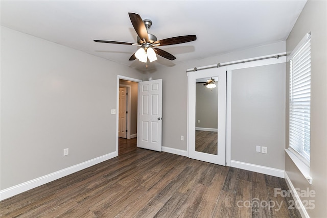 unfurnished bedroom featuring dark wood-type flooring, a closet, ceiling fan, and baseboards