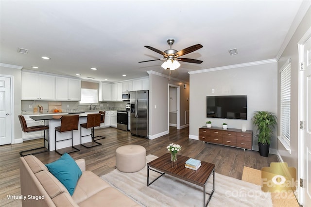 living room featuring a ceiling fan, visible vents, crown molding, and wood finished floors