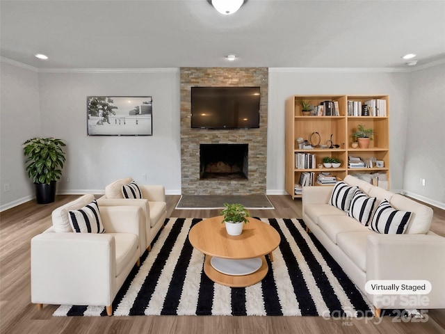 living room with hardwood / wood-style floors, a stone fireplace, and ornamental molding