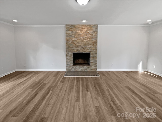 unfurnished living room with hardwood / wood-style flooring, ornamental molding, and a stone fireplace