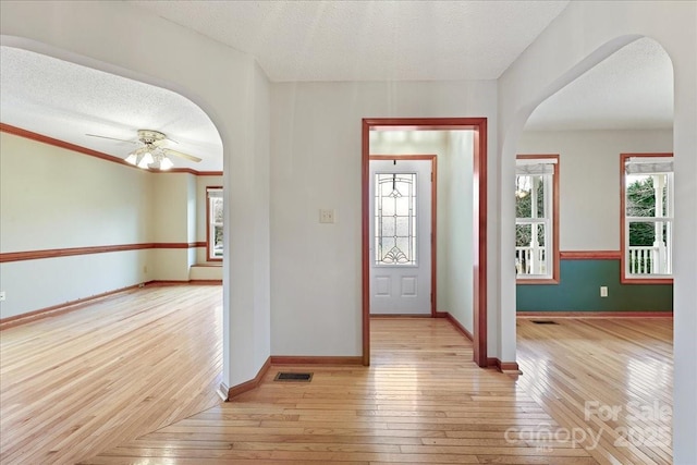 foyer featuring ceiling fan, light hardwood / wood-style flooring, and a textured ceiling