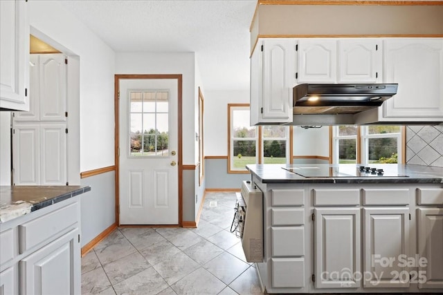 kitchen featuring white cabinetry, backsplash, black electric stovetop, a textured ceiling, and dark stone counters