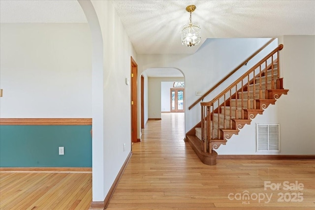 interior space featuring a chandelier, a textured ceiling, and light wood-type flooring