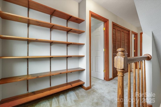 corridor with light colored carpet and a textured ceiling