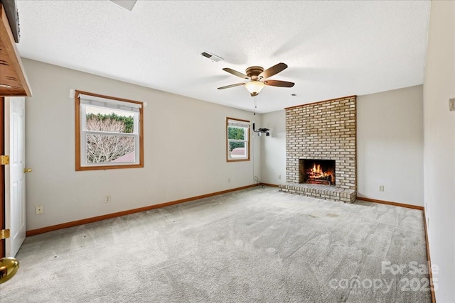 unfurnished living room featuring a brick fireplace, light colored carpet, a textured ceiling, and ceiling fan