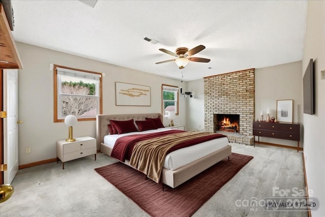 carpeted bedroom with a brick fireplace and ceiling fan