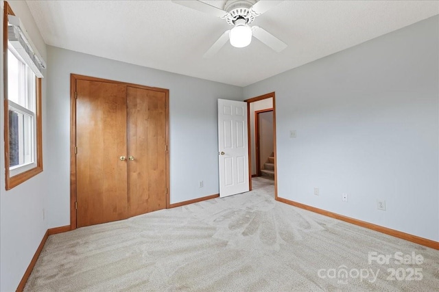 unfurnished bedroom with light carpet, ceiling fan, and a closet