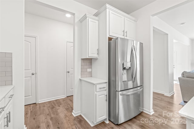 kitchen with tasteful backsplash, white cabinets, light countertops, and stainless steel fridge with ice dispenser