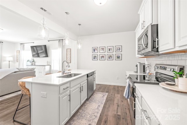 kitchen with a sink, visible vents, open floor plan, appliances with stainless steel finishes, and decorative backsplash