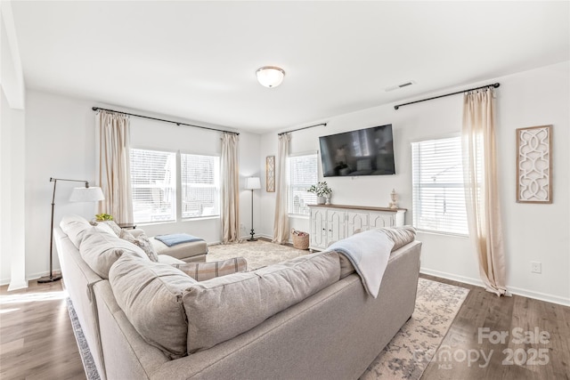 living area featuring wood finished floors, visible vents, and baseboards