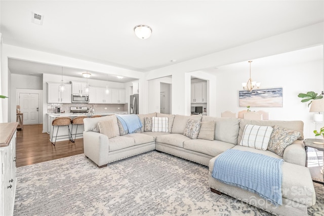 living area featuring wood finished floors, visible vents, and an inviting chandelier