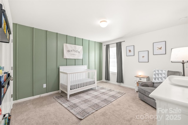 bedroom featuring a nursery area, baseboards, and light colored carpet