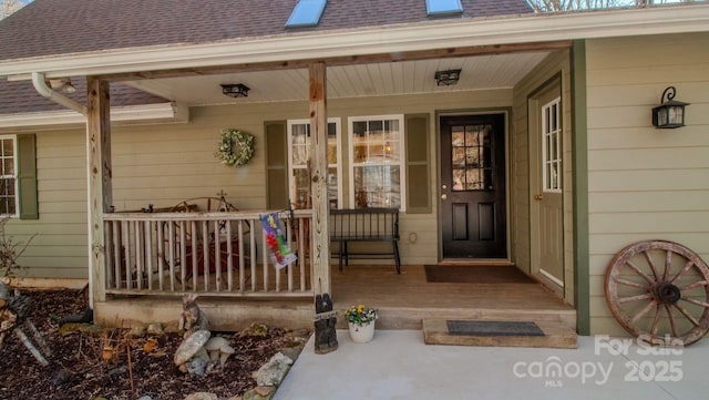 doorway to property featuring covered porch and roof with shingles