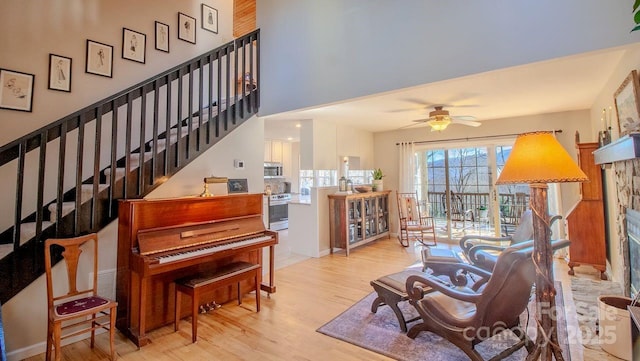 sitting room with ceiling fan, stairway, and wood finished floors