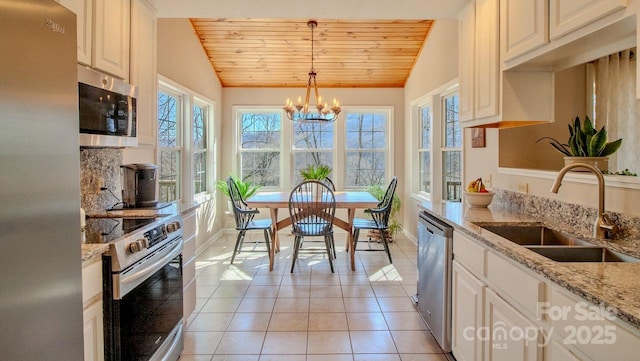 kitchen featuring lofted ceiling, light tile patterned floors, stainless steel appliances, a sink, and wood ceiling