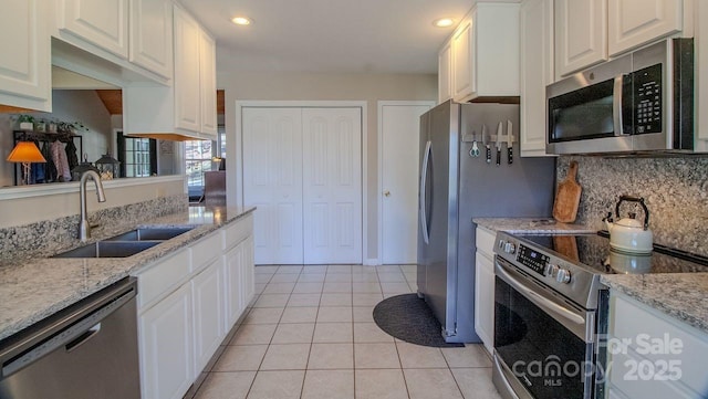 kitchen featuring stainless steel appliances, white cabinets, a sink, and light tile patterned floors