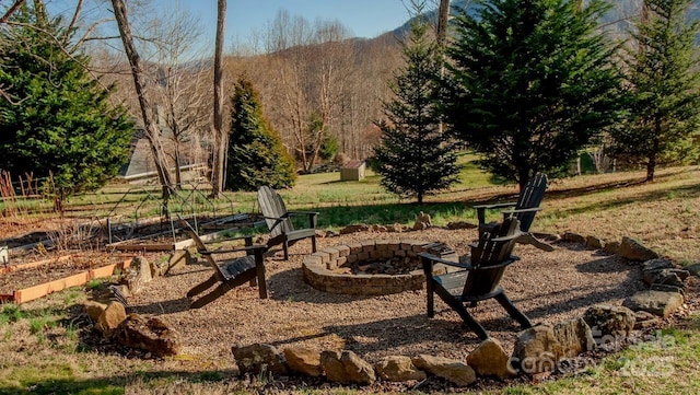 view of yard with a fire pit and a wooded view