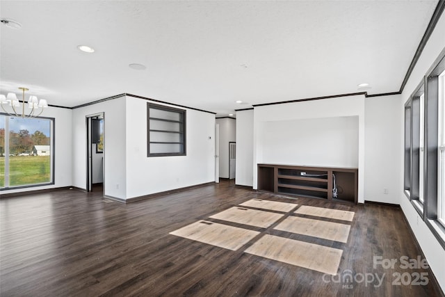 unfurnished living room featuring dark hardwood / wood-style flooring, a notable chandelier, and ornamental molding