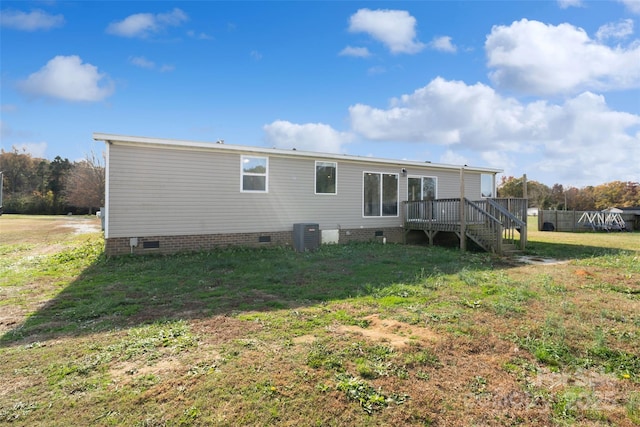 rear view of property featuring a wooden deck, central AC unit, and a lawn