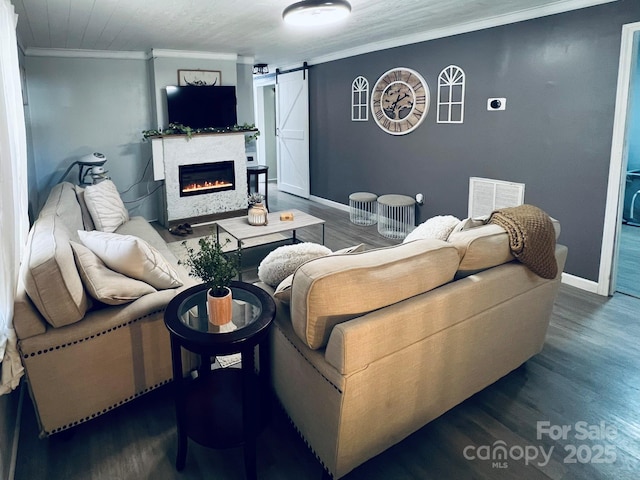 living room with crown molding, a barn door, and dark hardwood / wood-style floors