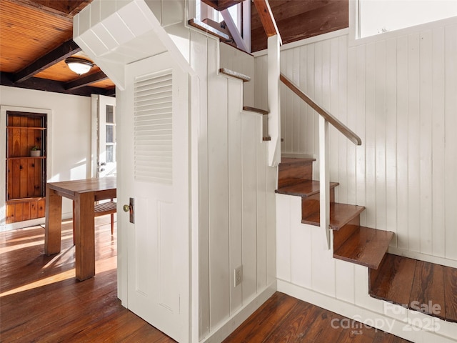 staircase featuring wood-type flooring and beamed ceiling