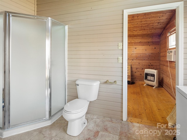 bathroom featuring a shower with door, heating unit, wooden walls, and toilet