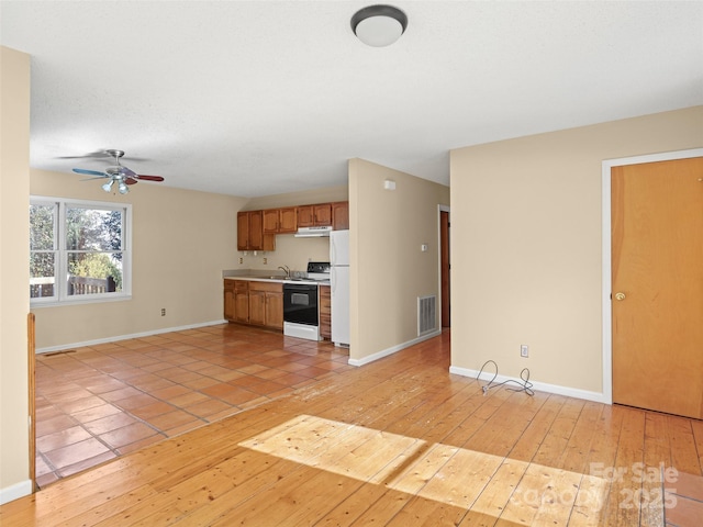 kitchen featuring sink, white refrigerator, electric range, ceiling fan, and light wood-type flooring