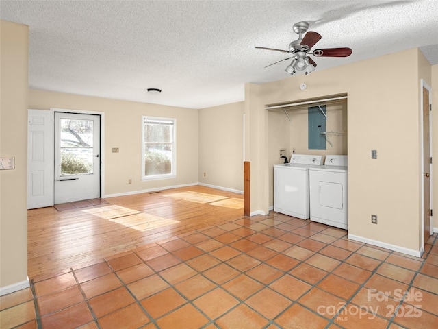 clothes washing area featuring washer and clothes dryer, ceiling fan, electric panel, wood-type flooring, and a textured ceiling