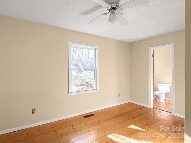 unfurnished bedroom featuring hardwood / wood-style floors, a textured ceiling, and ensuite bath