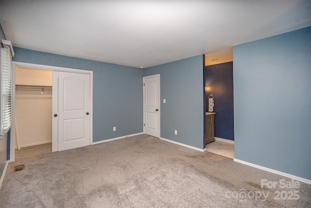 unfurnished bedroom featuring light colored carpet, ensuite bath, and a closet