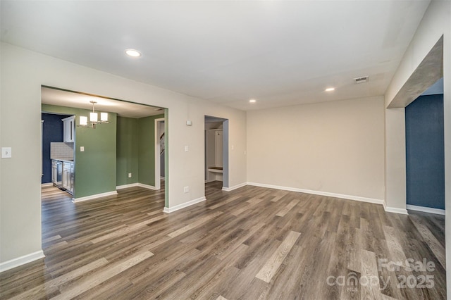 unfurnished room featuring an inviting chandelier and dark wood-type flooring